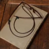 leather eyeglass lanyard in dark brown braided style on book