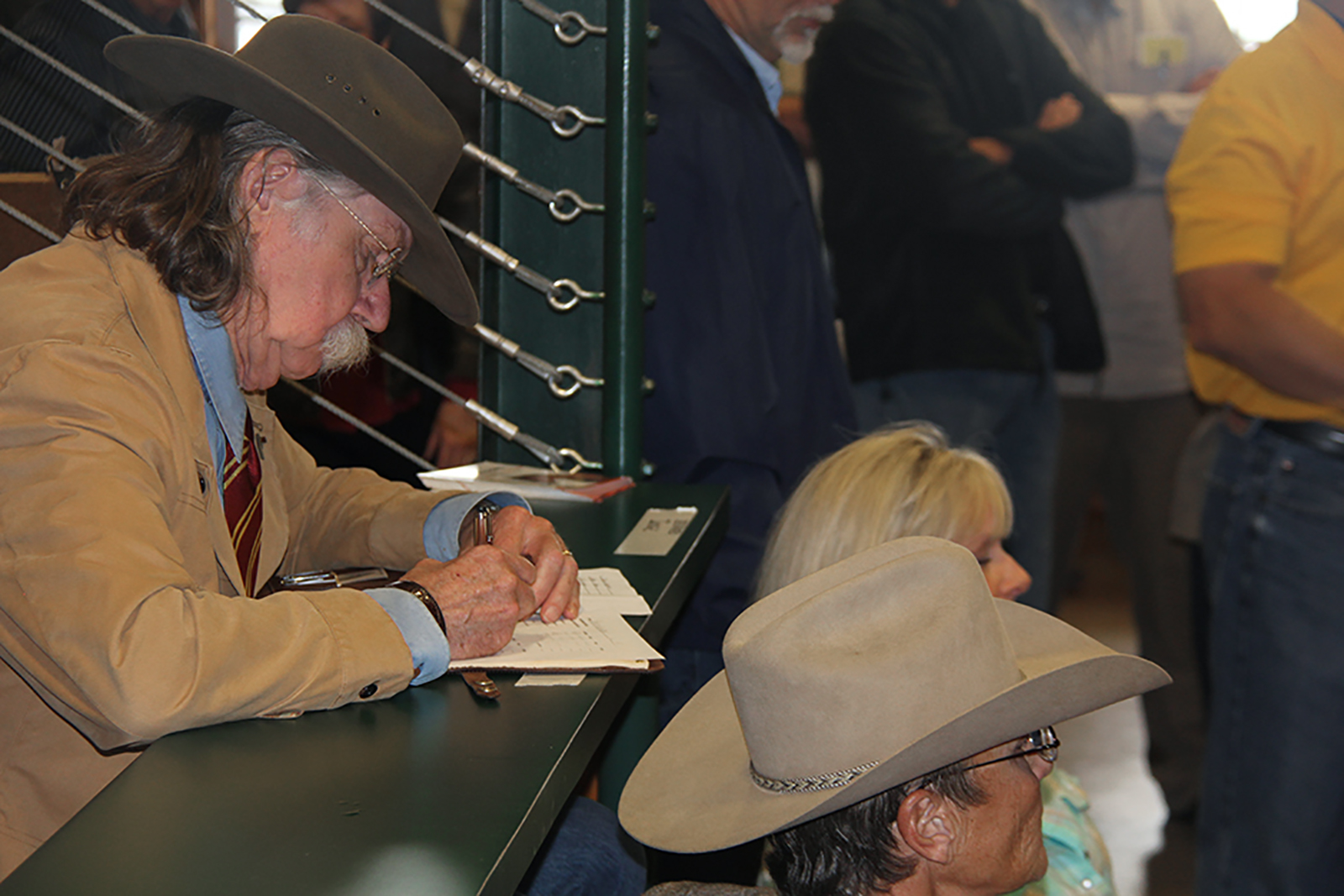 Colonel Littleton sitting at a narrow table, filling out a judging sheet for the auctioneering contest.