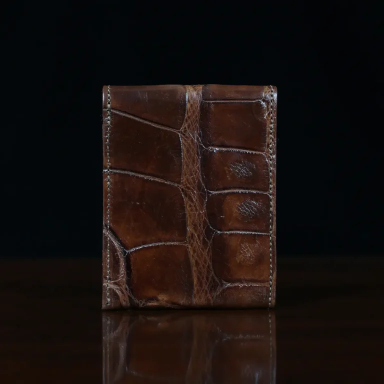 Front pocket wallet with flap in brown American Alligator - back view - 001 - on wood table with a dark background