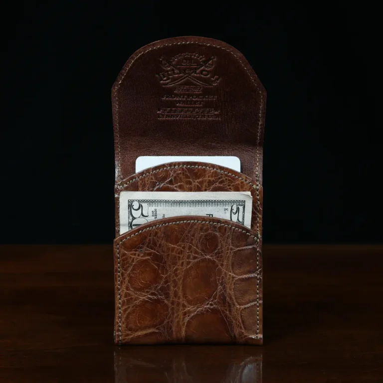 Front pocket wallet with flap in brown American Alligator - front open view with card - 001 - on wood table with a dark background