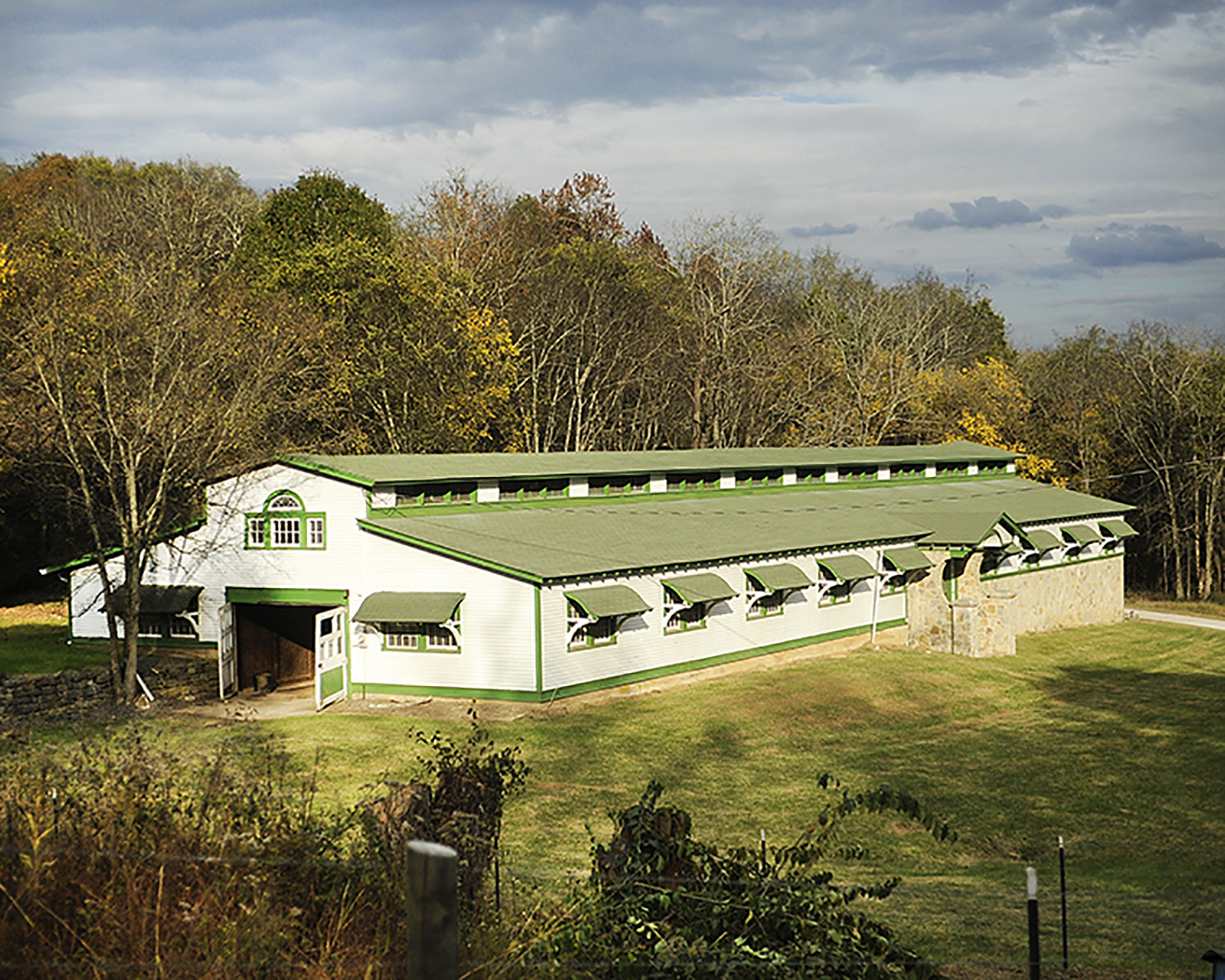 One of the elegant horse barns on the Milky Way Farms in Giles County TN, white walls with a green roof and green window trimming.