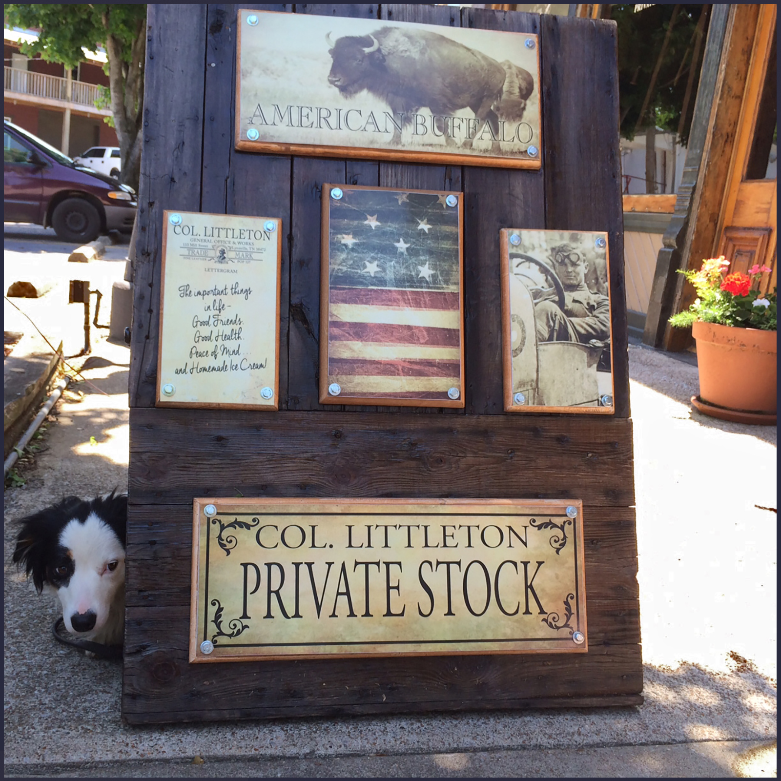 Colonel Littleton wooden a-frame sign for the Private Stock Store in Lynnville, TN, with a Australian Shepherd dog peeking out behind it.