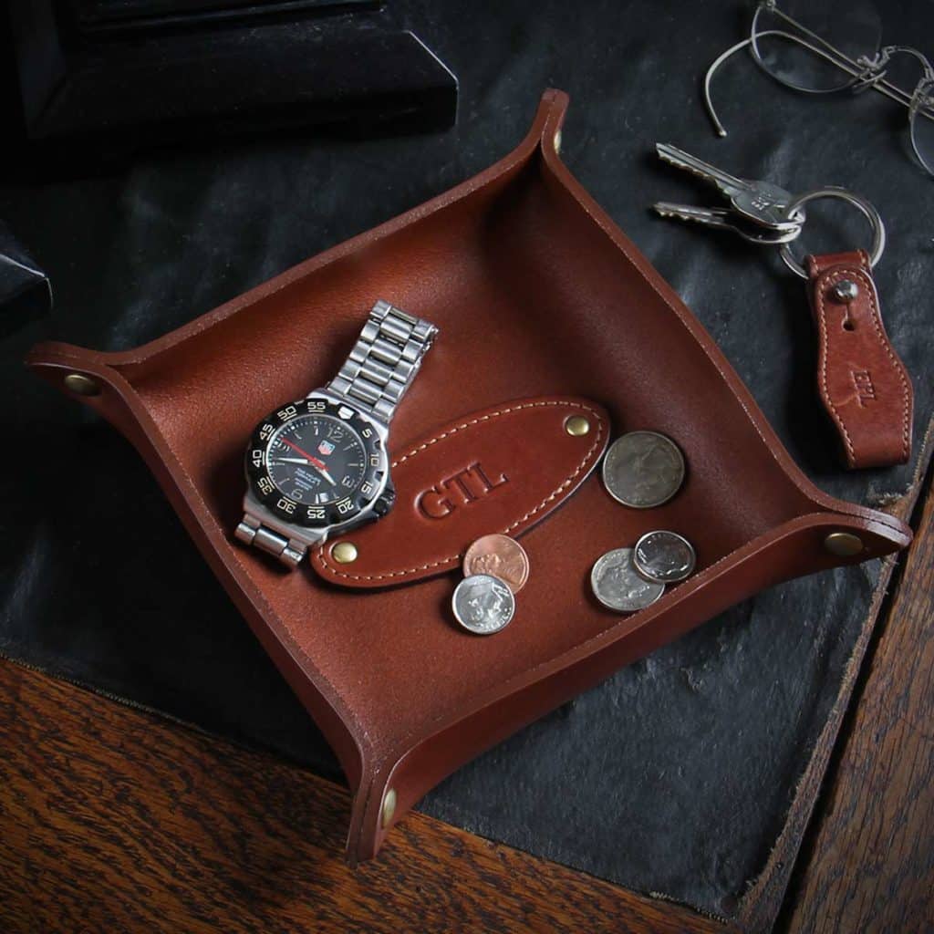 leather dresser caddy with a watch and spare change in it