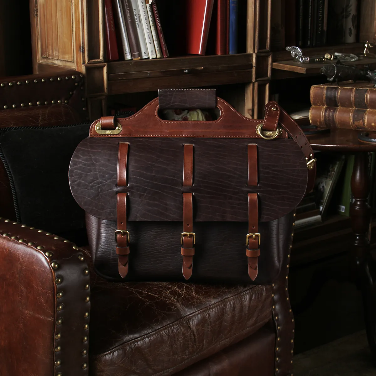 saddlebag briefcase in tobacco buffalo on a leather chair