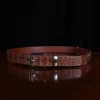 No. 4 Belt in American Alligator - X-Large - CB4XL-A-002 - coiled front view on a wooden table with black background