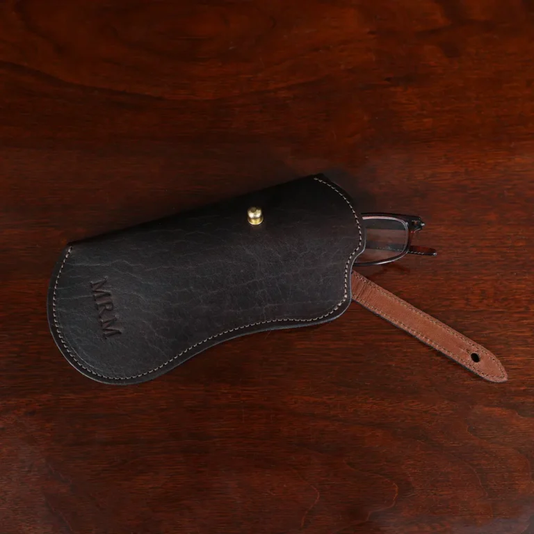 tobacco buffalo leather No. 2 Eyeglass Case on wood table with dark background - front open view with glasses