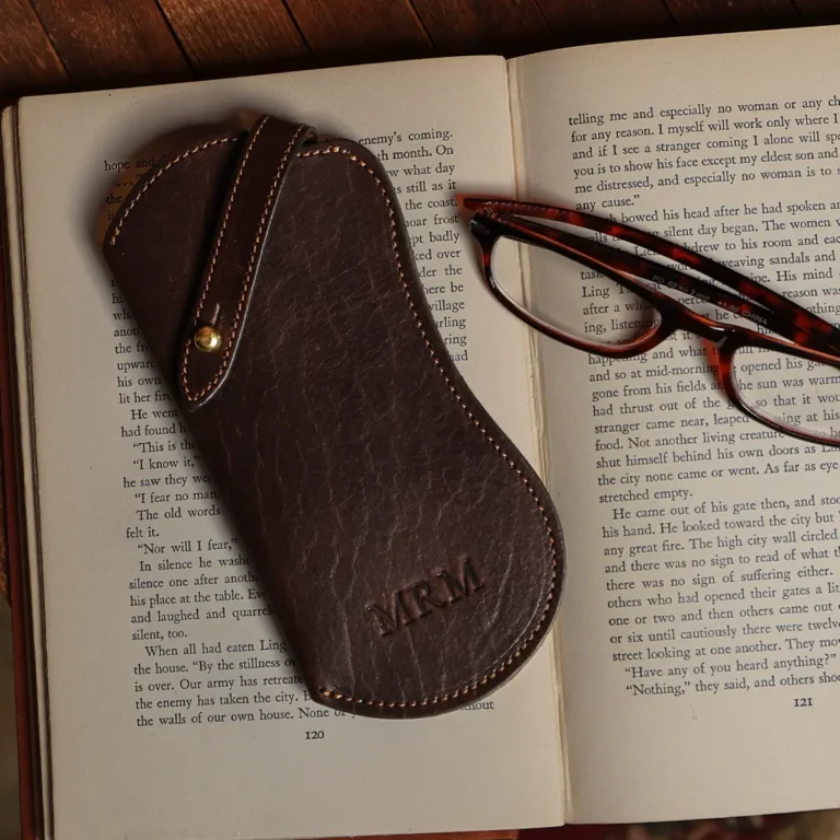 tobacco buffalo leather No. 2 Eyeglass Case on top of a book on wood table - front view