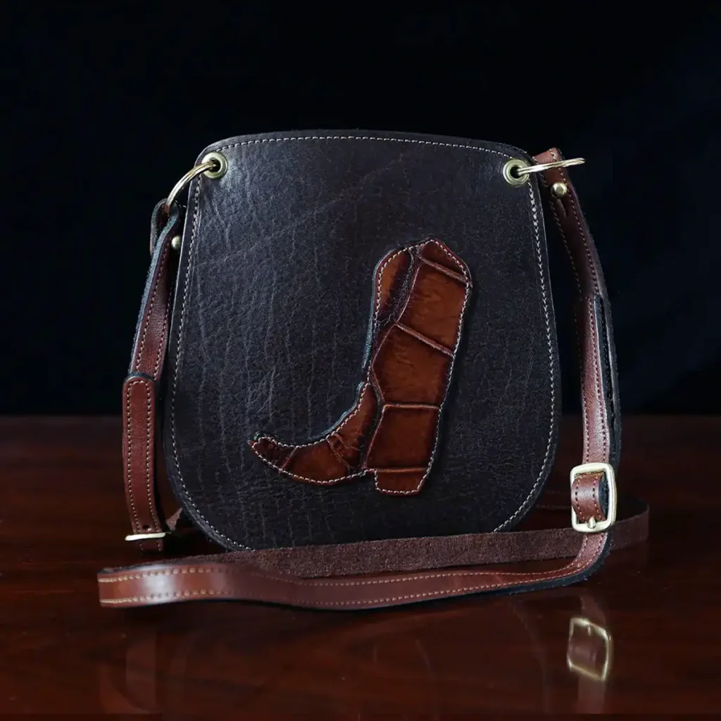 CL - dark brown leather Bella Bag small crossbody with boot on front made from alligator hide sitting on a wood table and black background - id 003